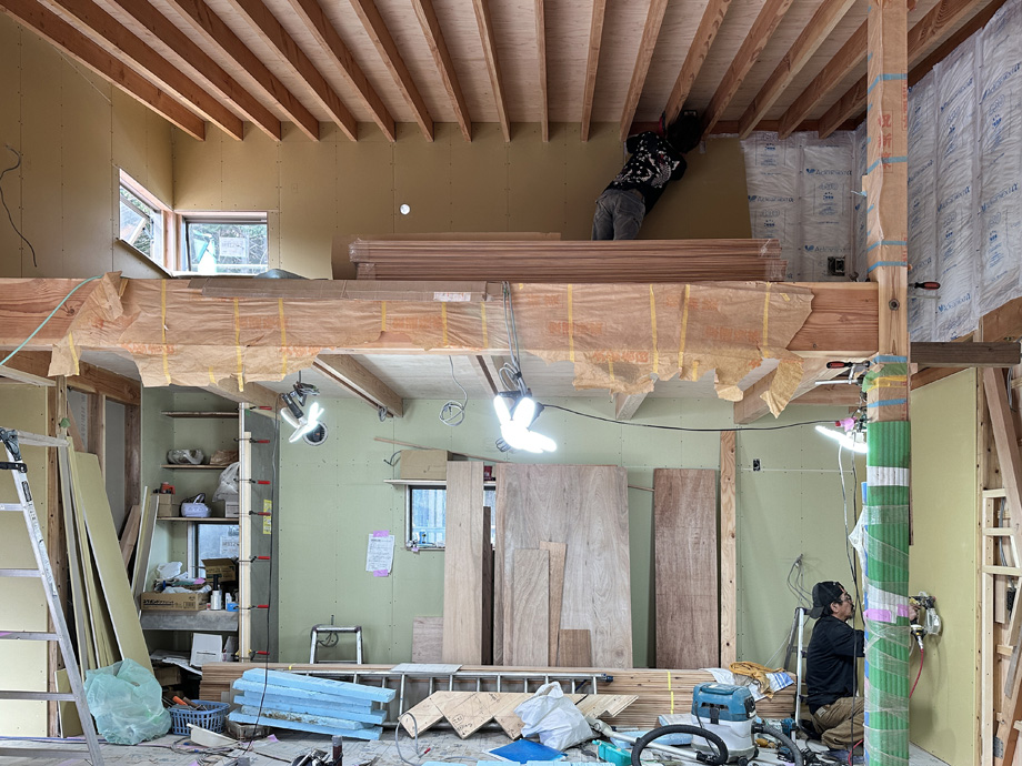 袖ケ浦市の平屋「紅の家」新築工事。ロフト部分に石膏ボードを張っている施工中の様子。梁あらわし天井の下で大工が作業している。