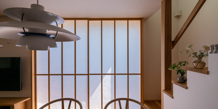 ダイニング越しに引き込み障子から柔らかな光が入る木の家のキッチン空間（埼玉県椿山の家）