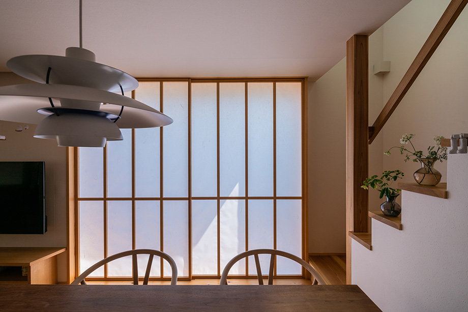 ダイニング越しに引き込み障子から柔らかな光が入る木の家のキッチン空間(埼玉県椿山の家)