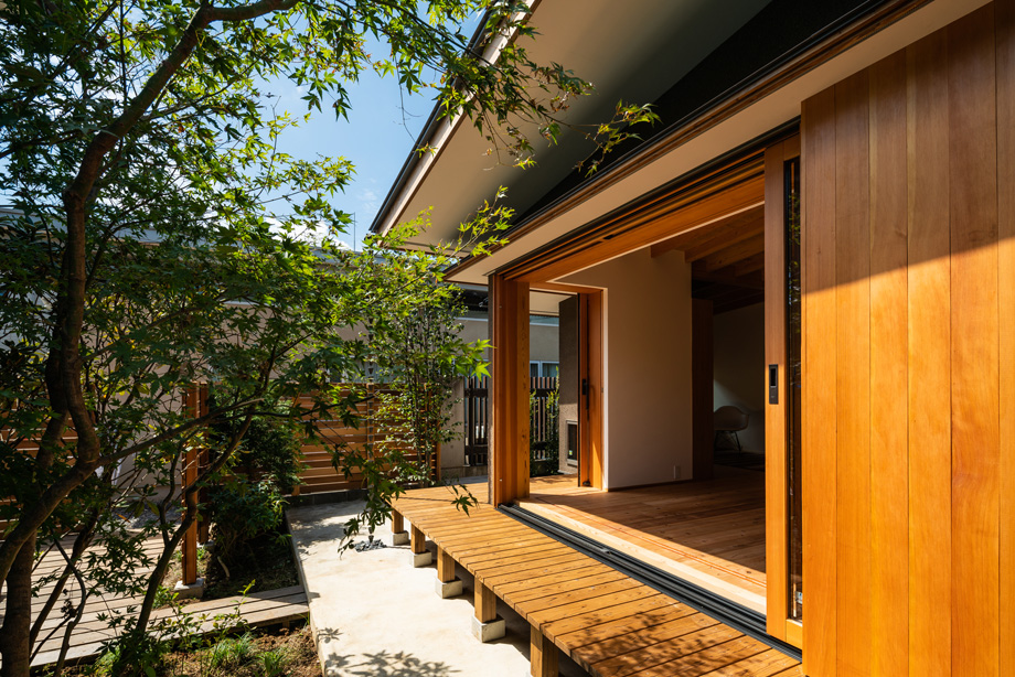 鎌ケ谷市「鎌ケ谷の家D」　木製全開サッシを全開した状態の外観　庭の緑と縁側