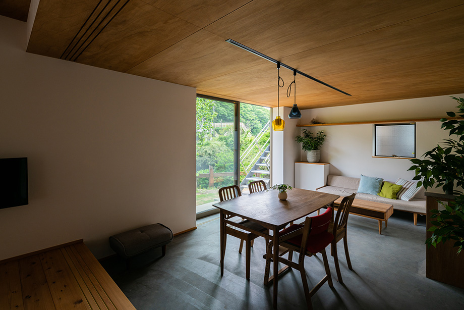 葉山「土間から四季を、呼吸する家」板の間から土間のダイニングを介して庭を見ている