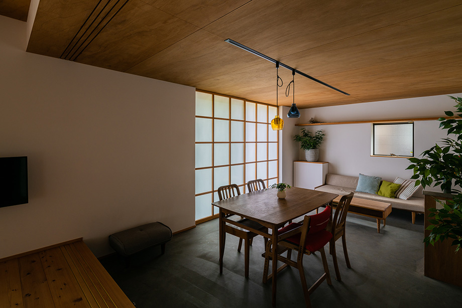 葉山「土間から四季を、呼吸する家」奥の板の間から土間のダイニングと引込障子を見ている
