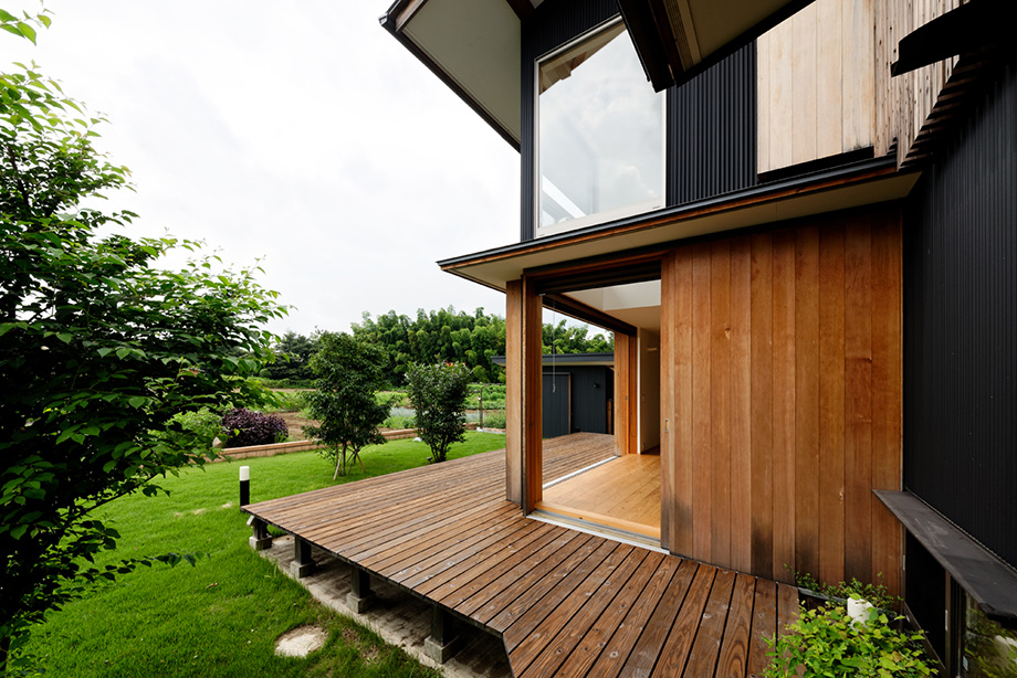 埼玉県「蓮田の家」木製全開サッシを全開した状態をデッキの東南方向から見ている。その奥にはリビングが越しに庭が見えている
