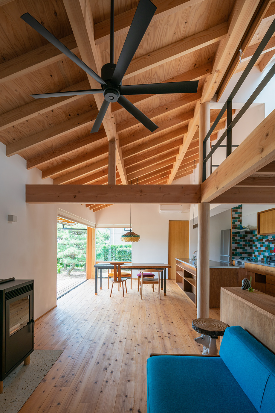 木製サッシで庭と繋がる開放的なダイニングと、落ち着きのあるリビング。大きな一つ屋根の下のワンルーム空間。