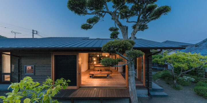 南房総市の平屋「白子の家」外観の夕景。木製サッシを閉じた状態　低くて深い軒。