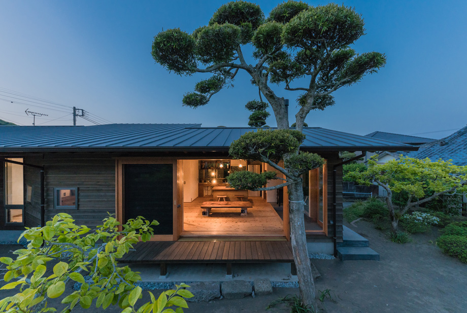 南房総市の平屋「白子の家」外観の夕景。木製サッシを閉じた状態 低くて深い軒。